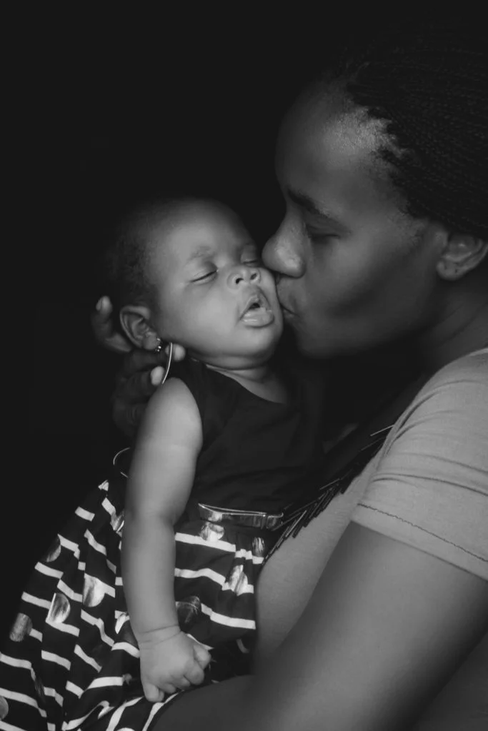 mother kissing her baby black and white