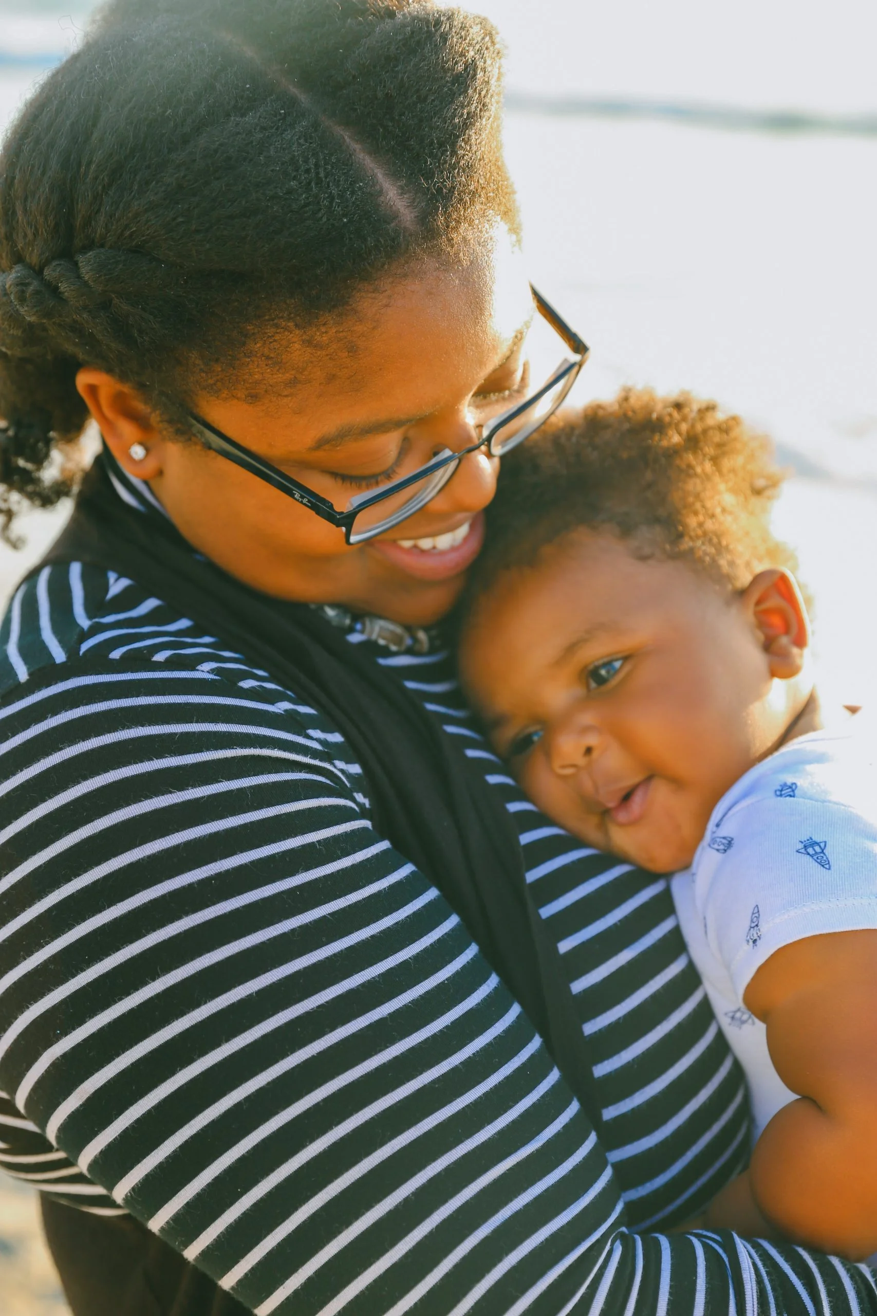 Black mother smiling while holding her baby in her arms. Happy mother after coaching