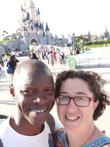 black man and white woman married couple smiling in front of disneyland castle