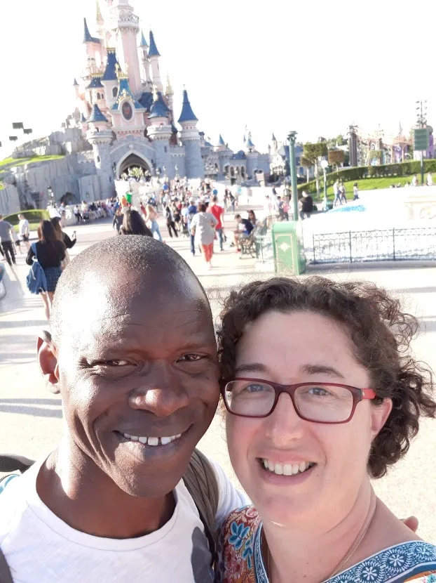 black man and white woman married couple smiling in front of disneyland castle