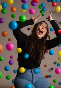 Juggling woman with many colourful balls falling on her