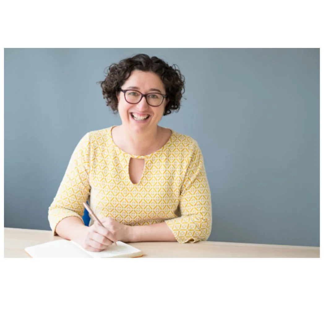 Photo of Peggy Cheyo sat at a table wearing a yellow top