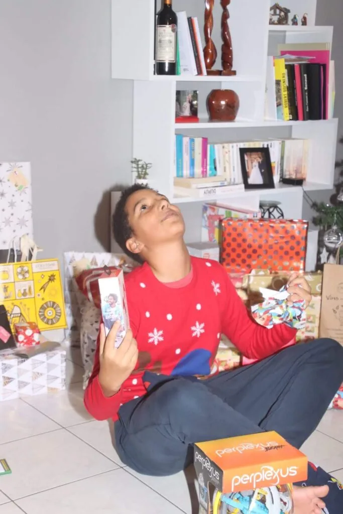 Autistic child wearing a christmas jumper looking up and holding presents
