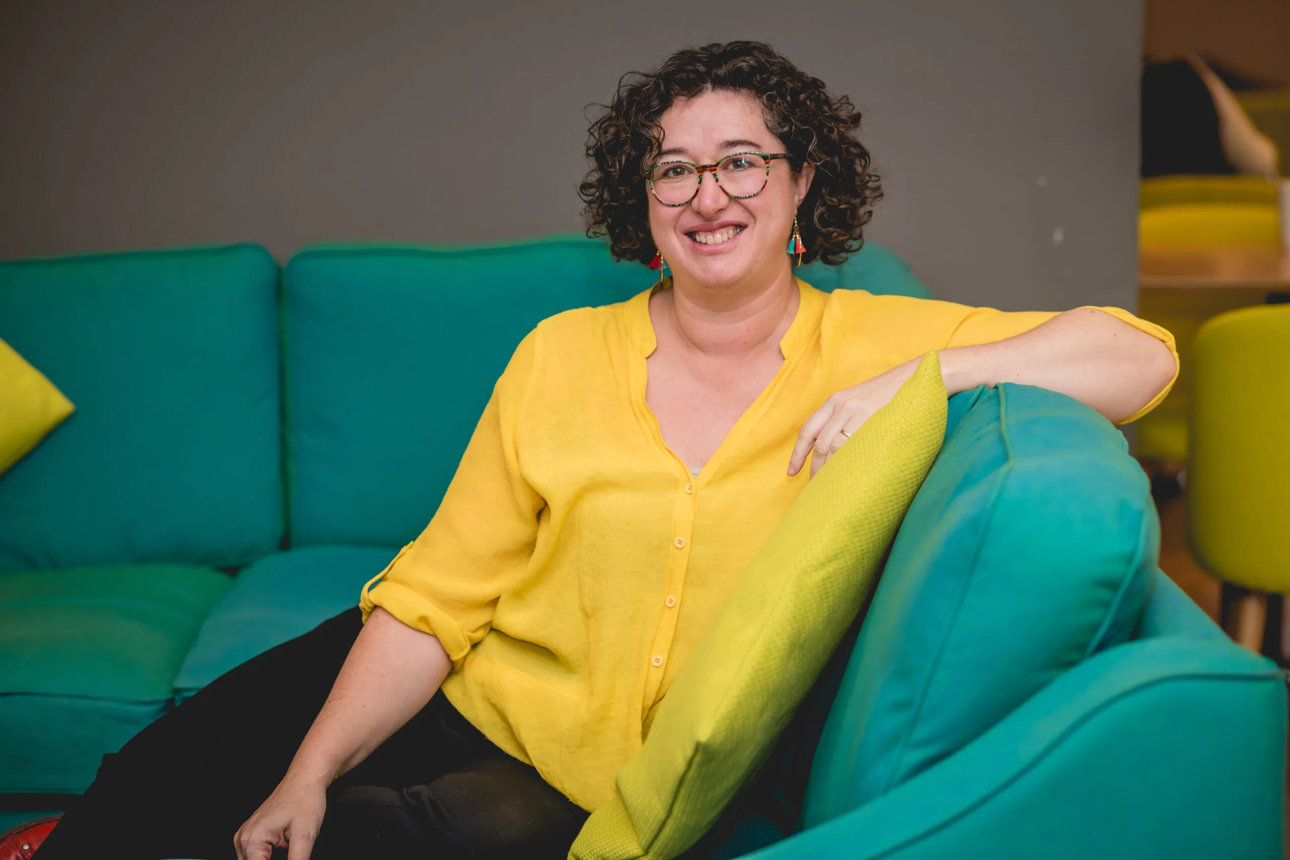 peggy Cheyo ADHD coach with a yellow shirt sitting on a green couch