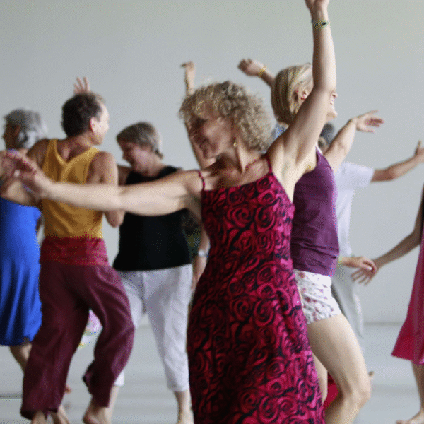 Biodanza session showing a woman wearing a red dress and man dancing in a group
