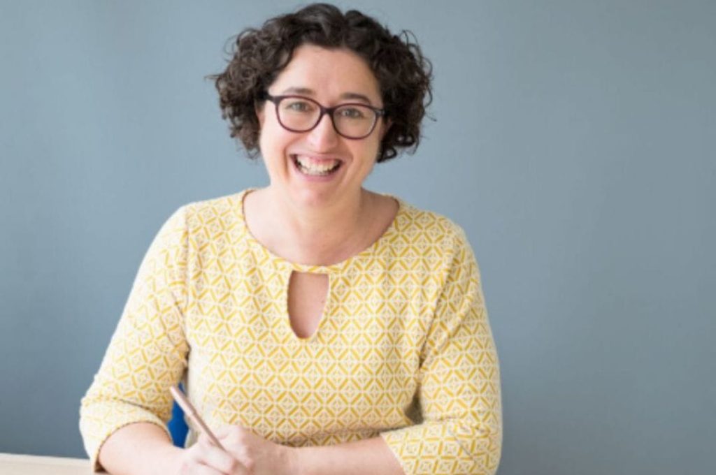 Peggy cheyo writing at her desk in a yellow top before an ADHD coaching session